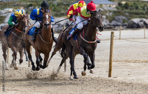 Galloping race horses and jockeys racing on the beach © Gabriel Cassan