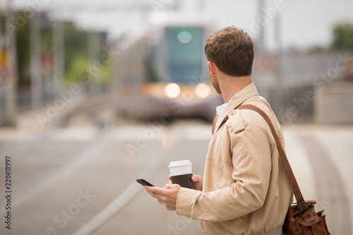 Man using mobile while looking at train