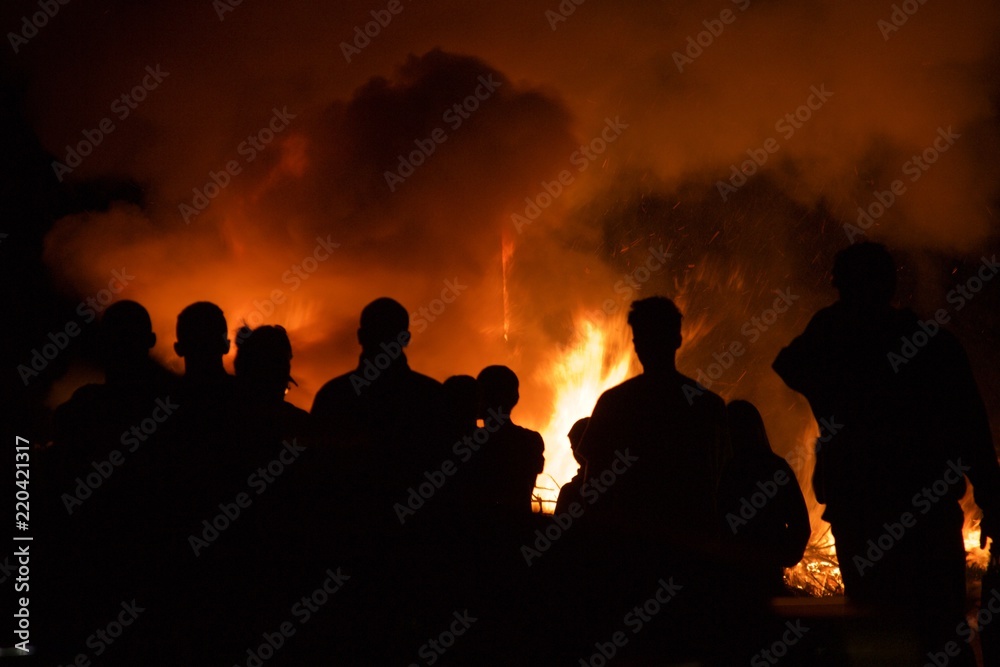Bush fire blazing with people standing around silhouetted by the flames. Dangerous in summer in california. Wildfire risk