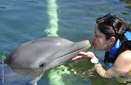 Woman holding and getting a kiss from a dolphin.