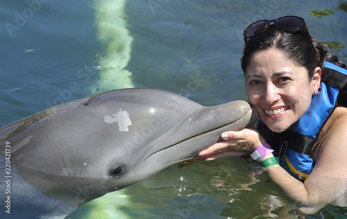 Woman holding and getting a kiss from a dolphin.