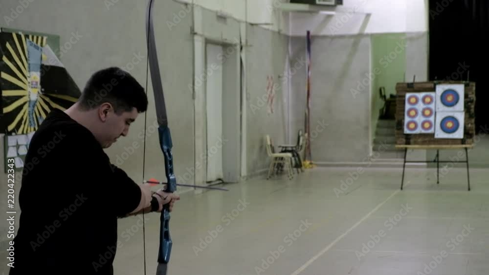 Young male archer practicing with bow and arrows shooting to a target Young male archer practicing with bow and arrows shooting to a target