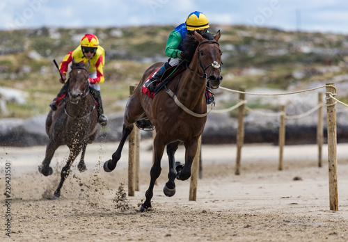 Galloping race horses and jockeys racing on the beach