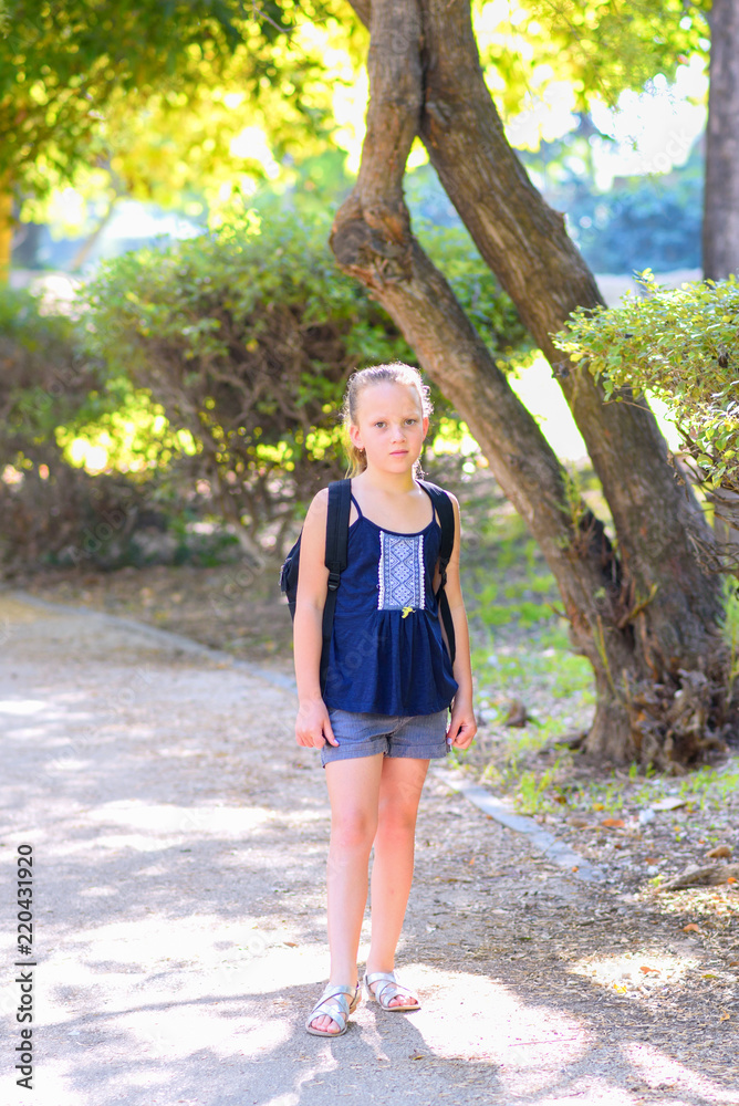 Teenager blonde kid Back to school. Child little girl with bag go to elementary school.Teen of primary school. Pupil go study with backpack.Sunny autumn park. Teenager blonde kid Back to school. Child little girl with bag go to elementary school.Teen of primary school. Pupil go study with backpack.Sunny autumn park.