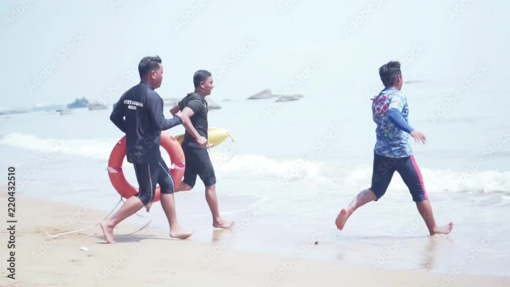 Three Asian Lifeguards Running To Rescue A Drowning Person Three Asian Lifeguards Running To Rescue A Drowning Person