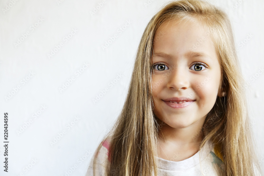 Portrait of happy little girl with long blonde hair smilng and showing positive emotions. Funny child with joyful facial expression. White isolated background, close up, copy space. Portrait of happy little girl with long blonde hair smilng and showing positive emotions. Funny child with joyful facial expression. White isolated background, close up, copy space.