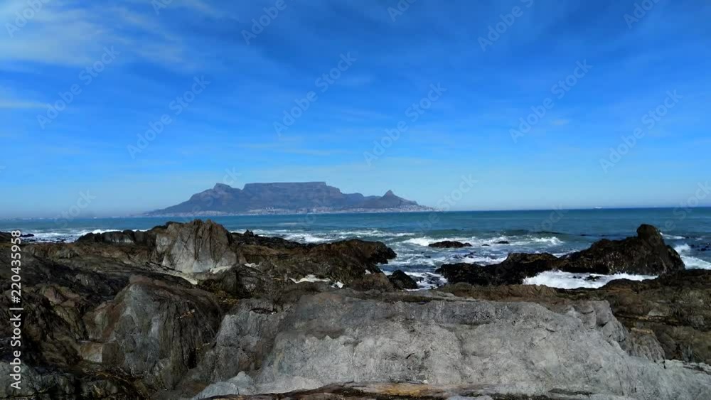Time lapse of Cape Town Table mountain with breaking waves in the foreground Time lapse of Cape Town Table mountain with breaking waves in the foreground