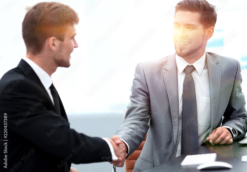 handshake of business partners sitting at a Desk. handshake of business partners sitting at a Desk.