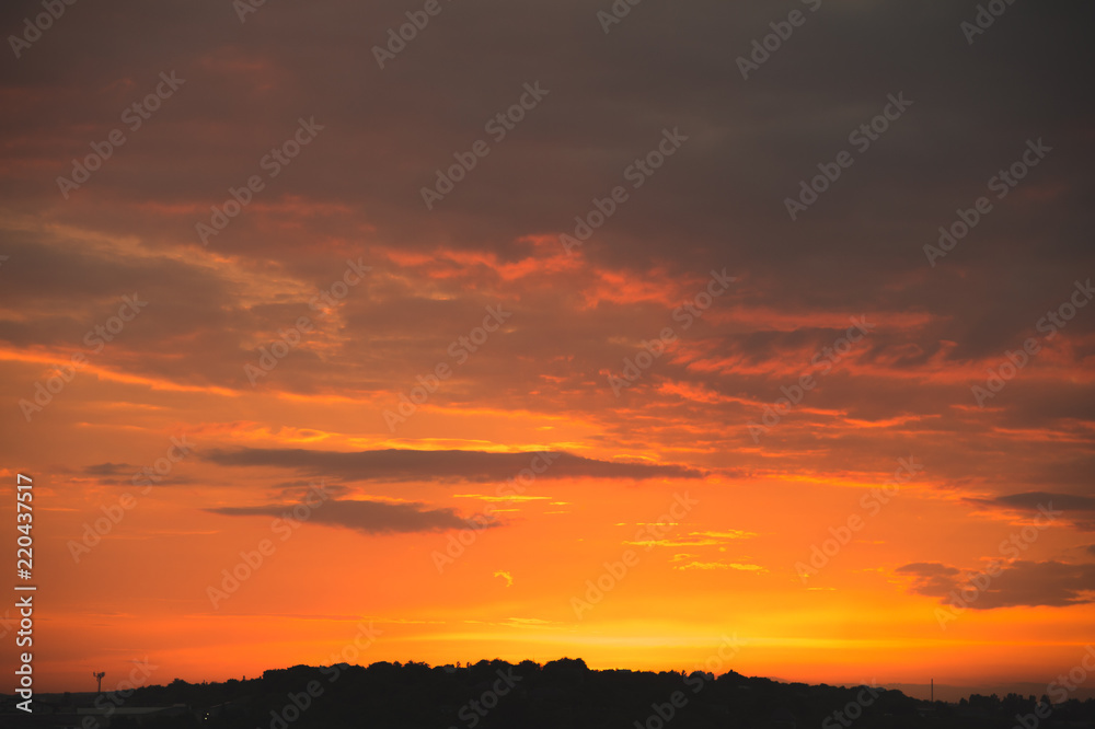 Evening sky after sunset with red clouds and the silhouette of the private sector of a small town Evening sky after sunset with red clouds and the silhouette of the private sector of a small town