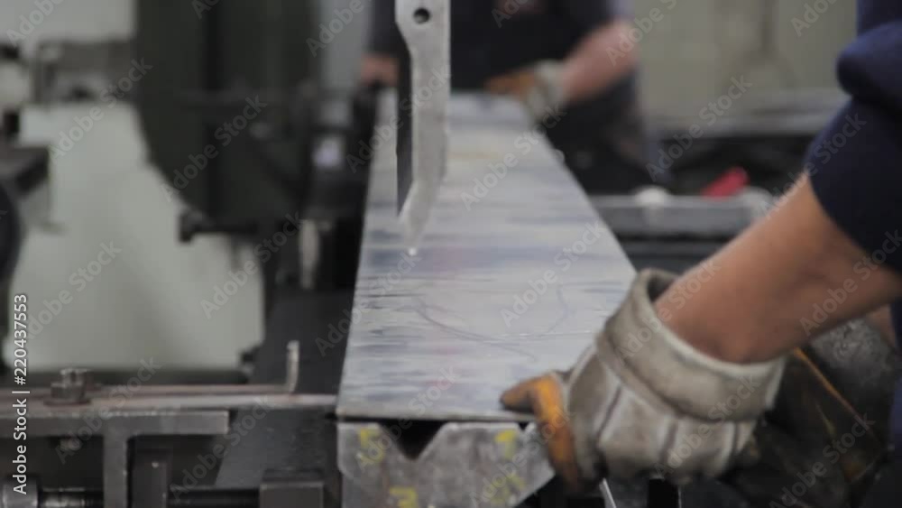 Two men placing a metal plate to fold in a hydraulic press sheet metal bending machine Two men placing a metal plate to fold in a hydraulic press sheet metal bending machine