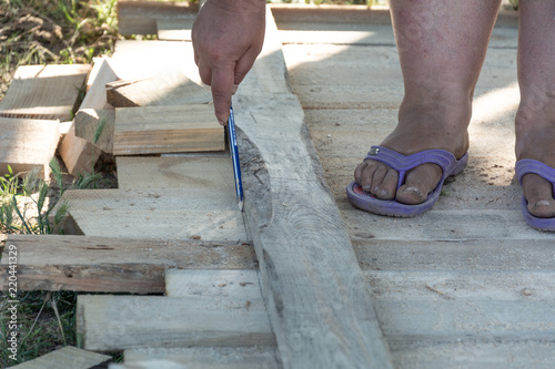 Carpenter's hands measuring a wooden board close-up image with the hands of a man and makes a mark with a pencil on.