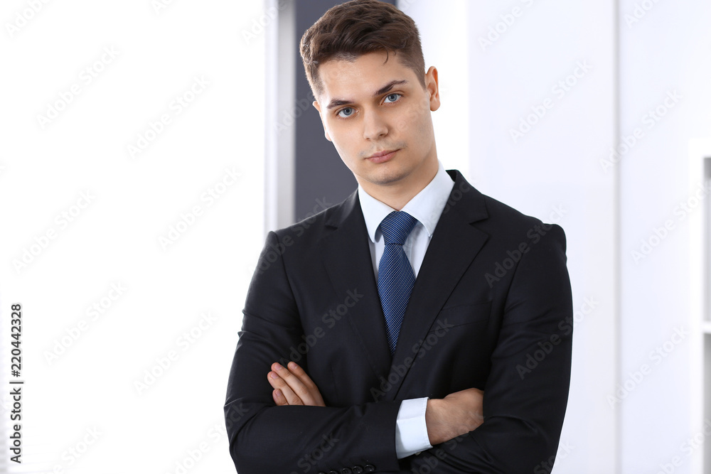 Young businessman standing in office with arms crossed. Business concept Young businessman standing in office with arms crossed. Business concept