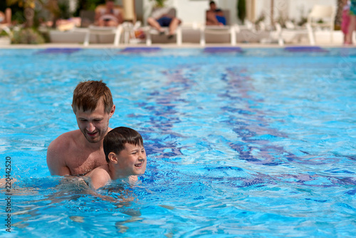 Father and son learning to swim in the swimming pool at the hotel. © Artem