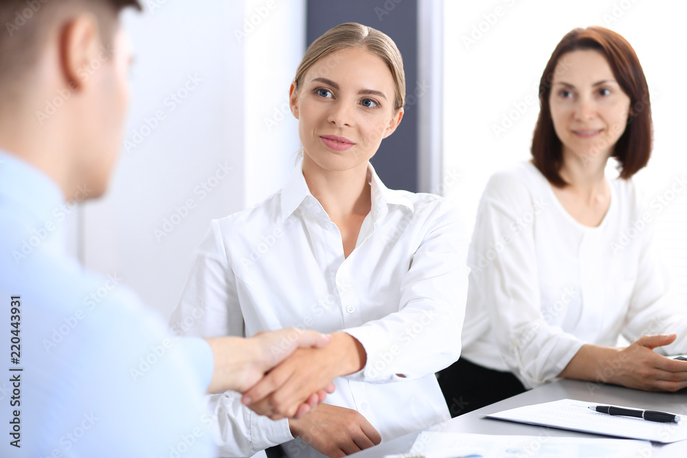 Business handshake by blonde woman and her partner at meeting. Concept of success and agreement Business handshake by blonde woman and her partner at meeting. Concept of success and agreement