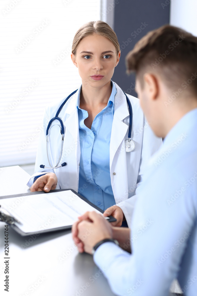 Doctor and patient in hospital. Beautiful blonde physician consulting business man about his health. Medicine concept Doctor and patient in hospital. Beautiful blonde physician consulting business man about his health. Medicine concept