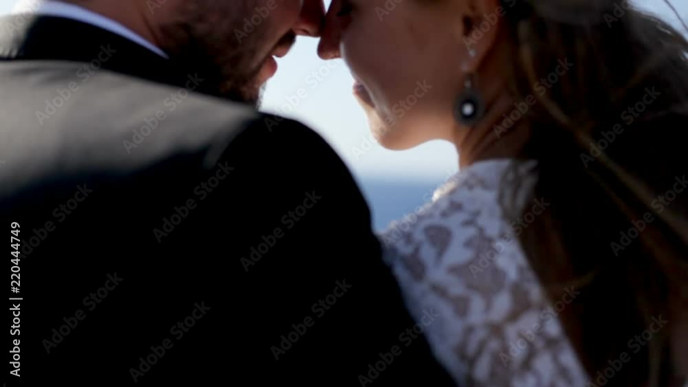 Happy bride and groom tenderly embrace on the stone shore of the sea on a sunny day. Greece Happy bride and groom tenderly embrace on the stone shore of the sea on a sunny day. Greece