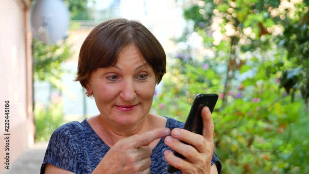 Woman shows on black smartphone phone outside near home Woman shows on black smartphone phone outside near home