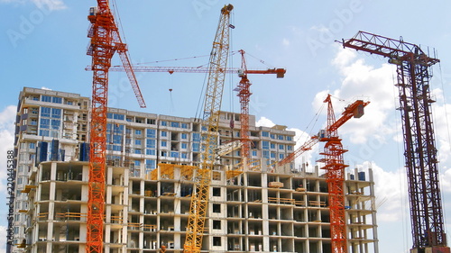 Construction site background. Four hoisting cranes near building.