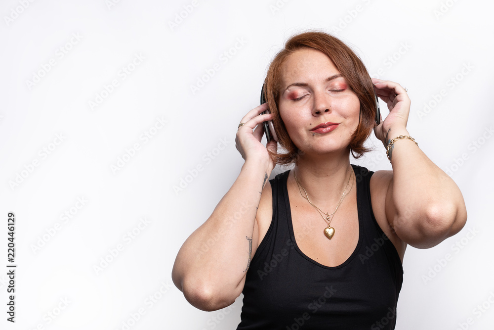 Woman enjoying music while touching her wireless headphones Woman enjoying music while touching her wireless headphones