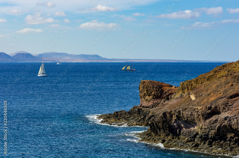Blick von Lanzarote nach Fuerteventura mit zwei Segelbooten und einem Motorboot auf dem Meer