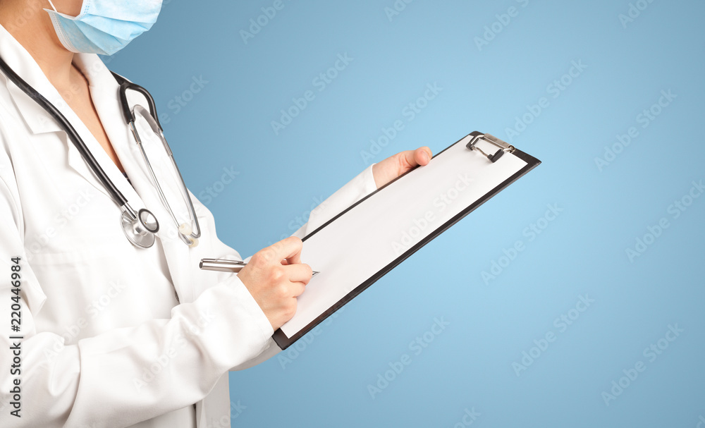 Female doctor holding notepad with blue background Female doctor holding notepad with blue background