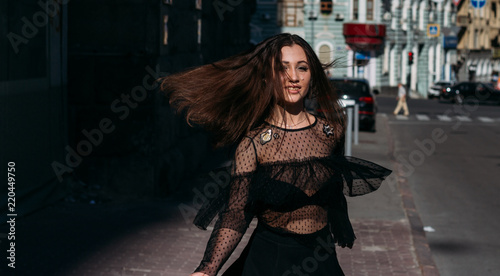 beautiful brunette whirls on a street in the middle of the city, laughs, smiles, happiness, fun