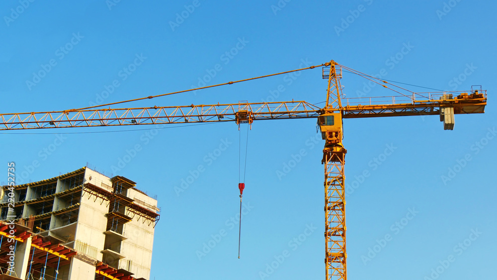 Tower crane near concrete building. Crane and building under construction.