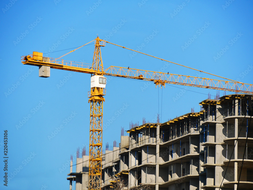 Crane and building against blue sky. Construction site with crane and concrete building.
