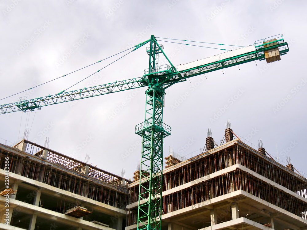 Construction of a multi-storey building. Crane and building under construction. Building site.