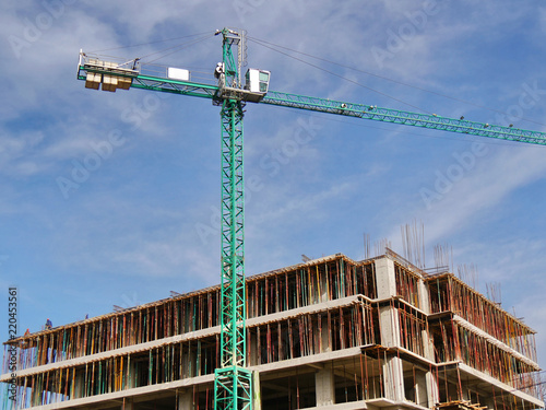 Crane and building against blue sky. Construction site background.