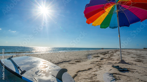 LOVERS KEY, FORT MYERS BEACH, FLOIRDA/USA 11/4/15: Paddle board on the beach underneath a rainbow umbrella.