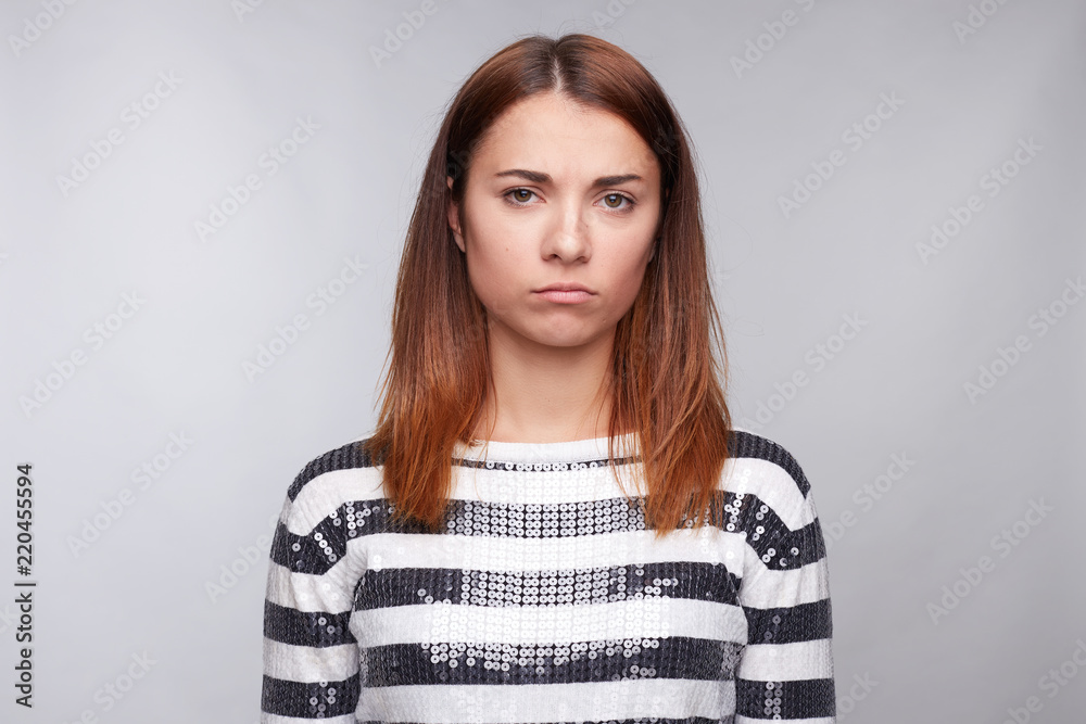 Dissatisfied tanned young woman wearing long sleeved black and white shirt, frowning face, looking angrily at camera, being displeased with her husband`s words. Negative emotions and reaction concept. Dissatisfied tanned young woman wearing long sleeved black and white shirt, frowning face, looking angrily at camera, being displeased with her husband`s words. Negative emotions and reaction concept.