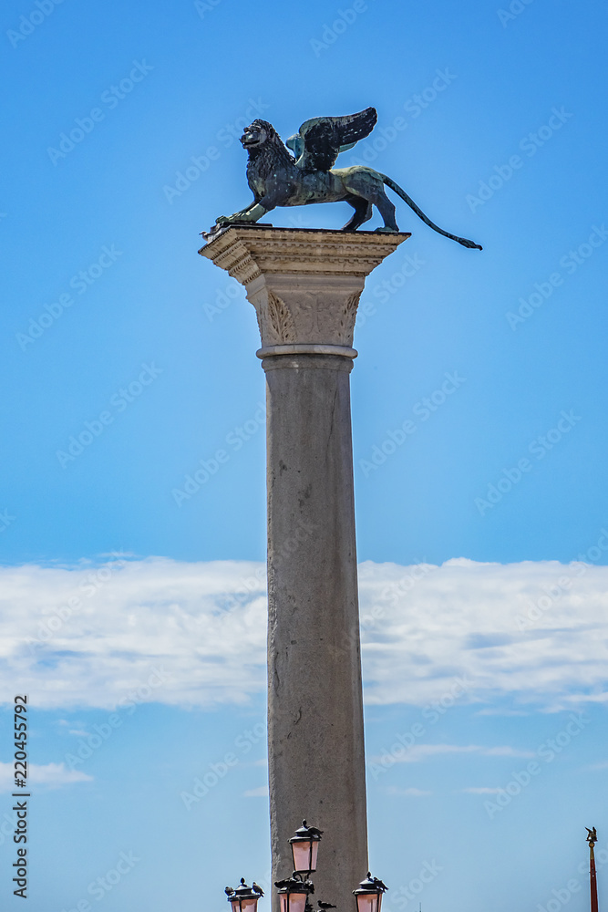 Lion of Venice at Ancient column (1268), bronze winged lion sculpture in the Piazza San Marco - the symbol of Venice city. Venice, Italy. Venice - UNESCO world heritage Site. Lion of Venice at Ancient column (1268), bronze winged lion sculpture in the Piazza San Marco - the symbol of Venice city. Venice, Italy. Venice - UNESCO world heritage Site.