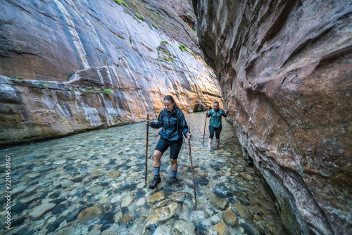 Two Young Female Friends Hiking Through the Narrows, Zion National Park, Utah - USA
