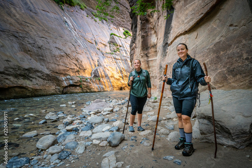 Two Young Female Friends Hiking Through the Narrows, Zion National Park, Utah - USA