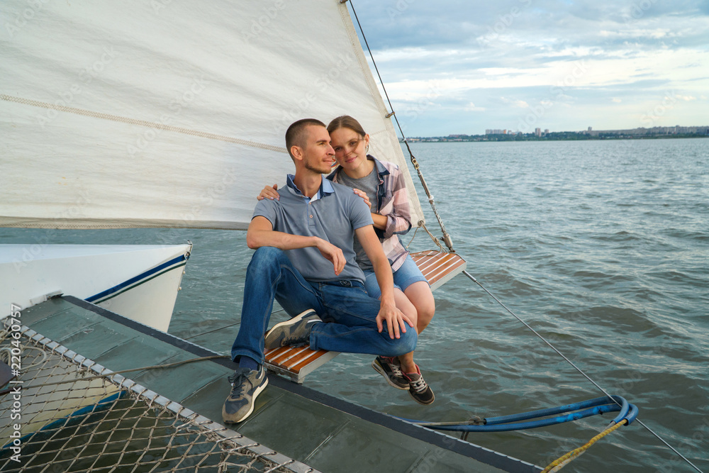 Young Couple hugging, sitting on boat enjoying summer day
