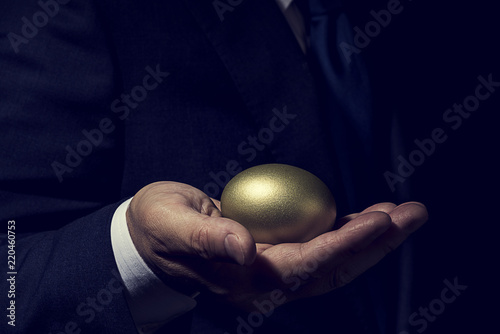 金の卵を手に持ったビジネスマン