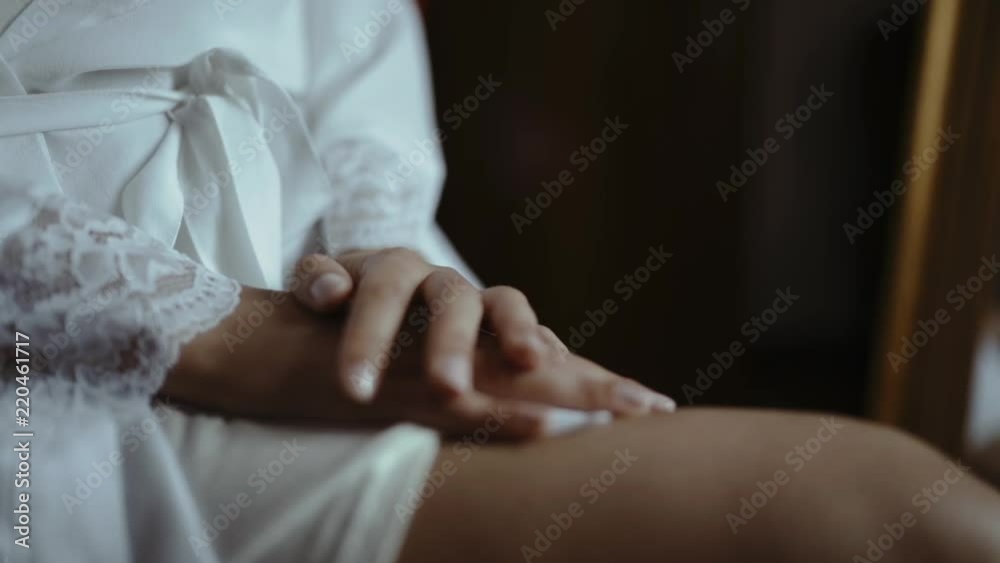 Detail of woman sitting in white silk dressing gown. Detail of woman sitting in white silk dressing gown.
