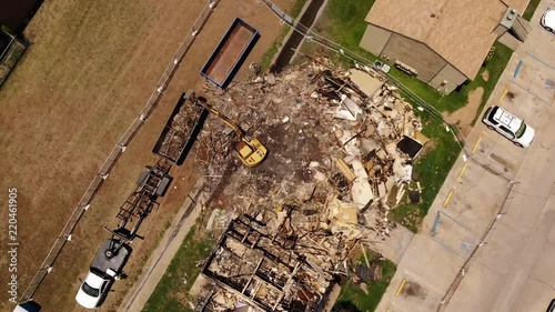 Aerial shot of a drone. The drone is rising and captures a by fire destroyes house. The building gets demolished by an excavator. photo