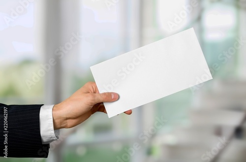 Hand of business man in grey suit holding white card