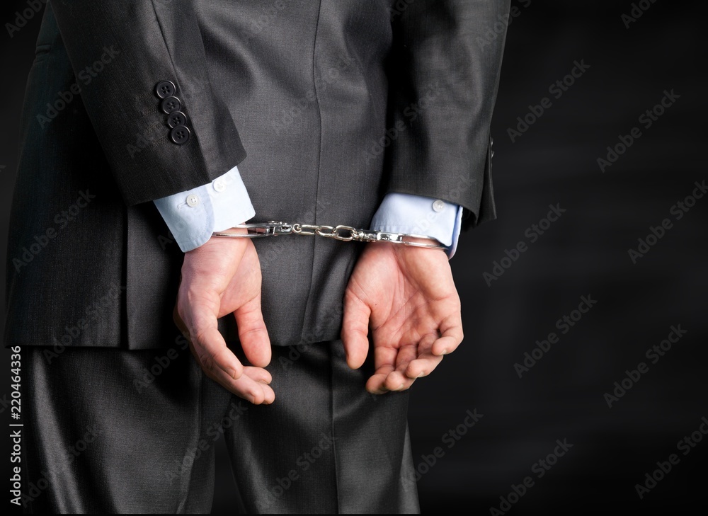 Cropped image of male hands in handcuffs behind his back