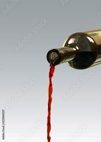 Red wine pouring from bottle on white background
