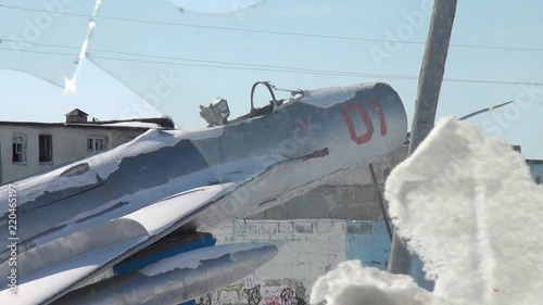 View of airplane monument to aviators through frozen broken window. MiG-19 aircraft in honor of the pioneers and defenders of the sky of Chukotka. Way to ghost town Gudym. Unique place for stalkers. photo