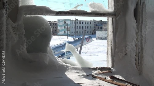 View of airplane monument to aviators through frozen broken window. MiG-19 aircraft in honor of the pioneers and defenders of the sky of Chukotka. Way to ghost town Gudym. Unique place for stalkers. photo