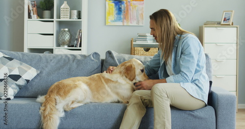 Wallpaper Mural Caucasian attractive young man with long fair hair sitting on the couch and his labrador dog lying next to him. Man petting it. Indoors. Torontodigital.ca