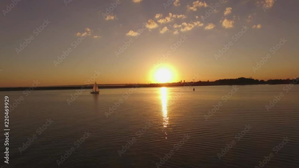 Yacht sails across calm still sea water at a sunset with reflection sun Yacht sails across calm still sea water at a sunset with reflection sun