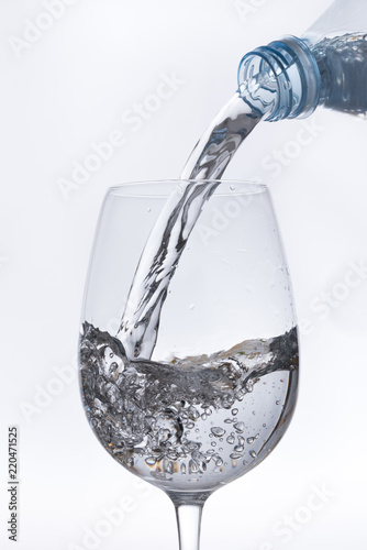 Water bottle, pouring its contents into a glass cup
