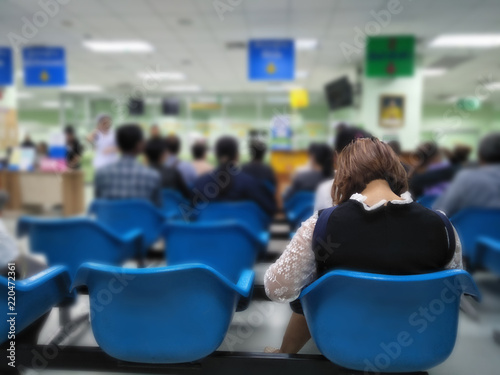 young woman sit on blue chair at front the emergency room and many people waiting medical and health services to the hospital,patients waiting treatment at the hospital,blurred image of people photo