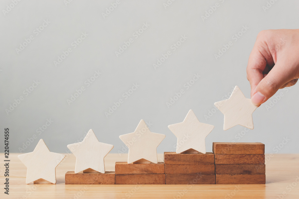 Hand putting wooden five star shape on table. The best excellent business services rating customer experience concept - obrazy, fototapety, plakaty 