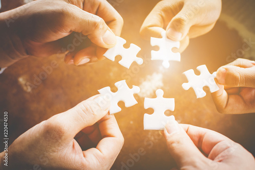 Hand of diverse people connecting jigsaw puzzle. Concept of partnership and teamwork in business photo